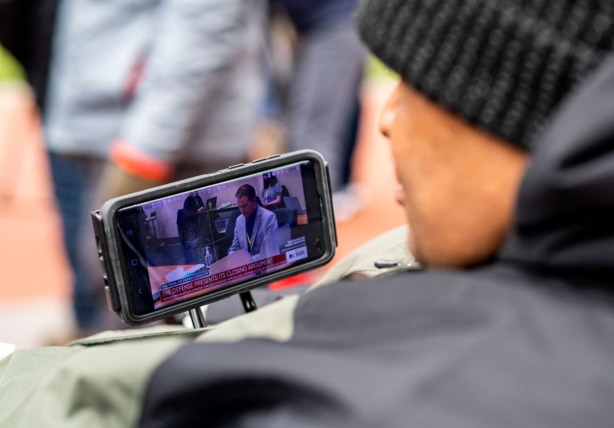 Michael Jones watches closing arguments on his phone outside the Hennepin County Government Center on April 19.