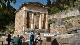 Tourists at the ancient ruins of the  Treasury of the Athenians in the Archaeological Site of Delphi  (UNESCO World Heritage Site, 1987) on April 4, 2021 in Delphi, Greece. The ruins of the archaeological site and monuments of Delphi had a great influence on the ancient world in the 6th century B.C, as evidenced by the various monuments built by most of the important ancient Greek city-states, demonstrating unity of the ancient Greek world. (Photo by Milos Bicanski/Getty Images)