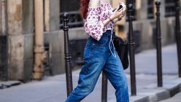 A passerby wears an off-shoulder white and pink floral print ruffled top, blue cropped jeans, on June 25, 2020 in Paris, France. 
