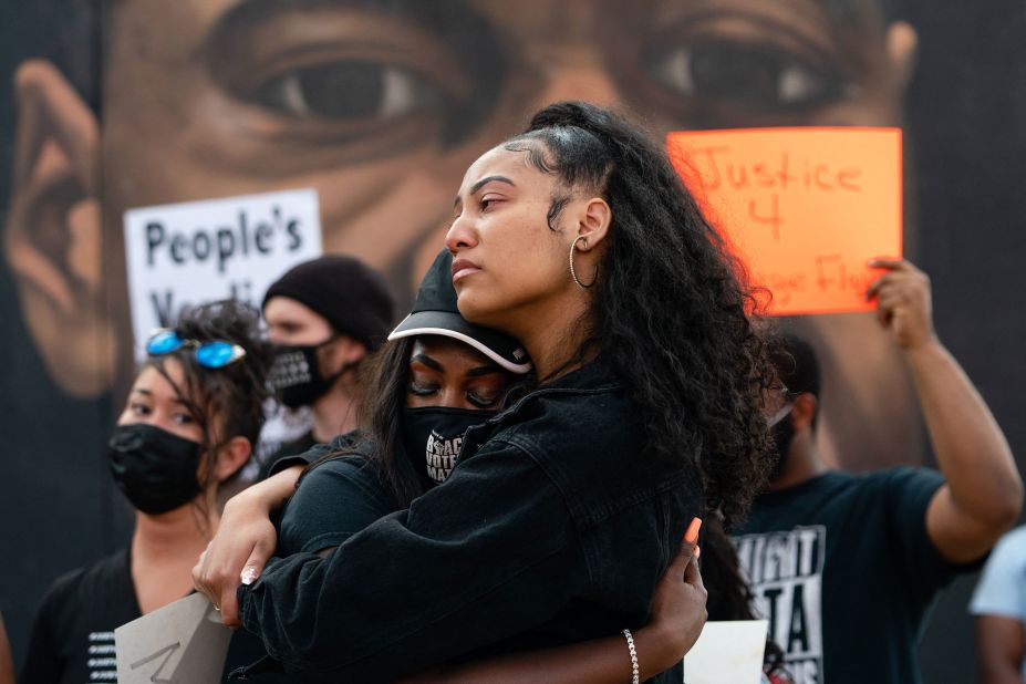 People embrace in front of a mural of George Floyd in Atlanta.