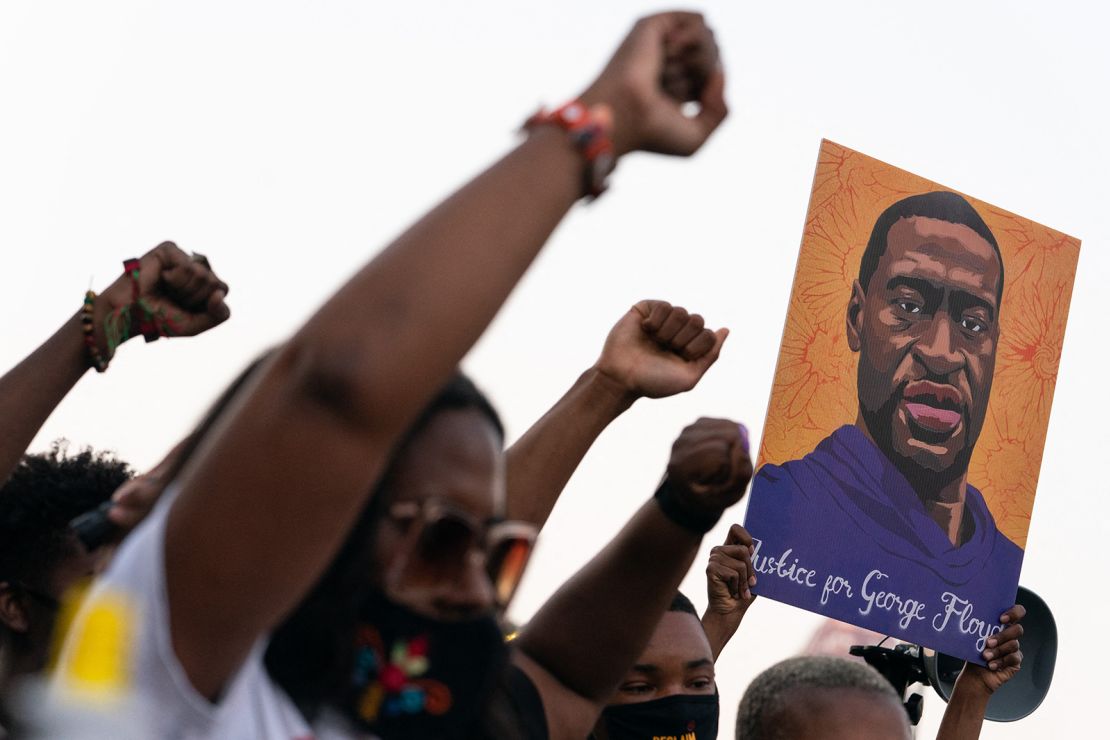 People raise their fists and hold a portrait of George Floyd during a rally following the guilty verdict the trial of Derek Chauvin on April 20, 2021, in Atlanta.