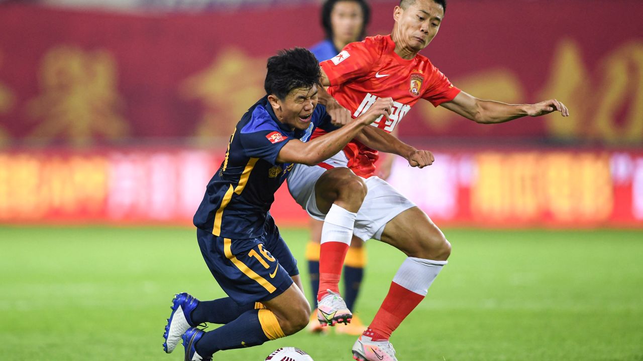 Chen Junle (left) of Guangzhou City fights for the ball with Huang Bowen of Guangzhou FC during the opening match of the new Chinese Super League season.