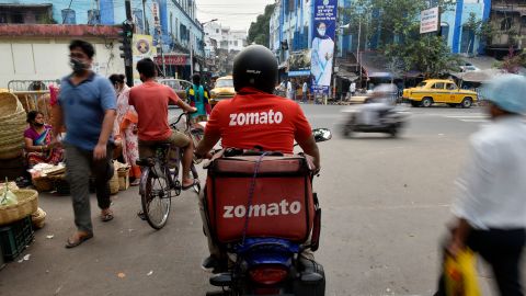 A Zomato delivery rider waits to cross a road in Kolkata, India. 