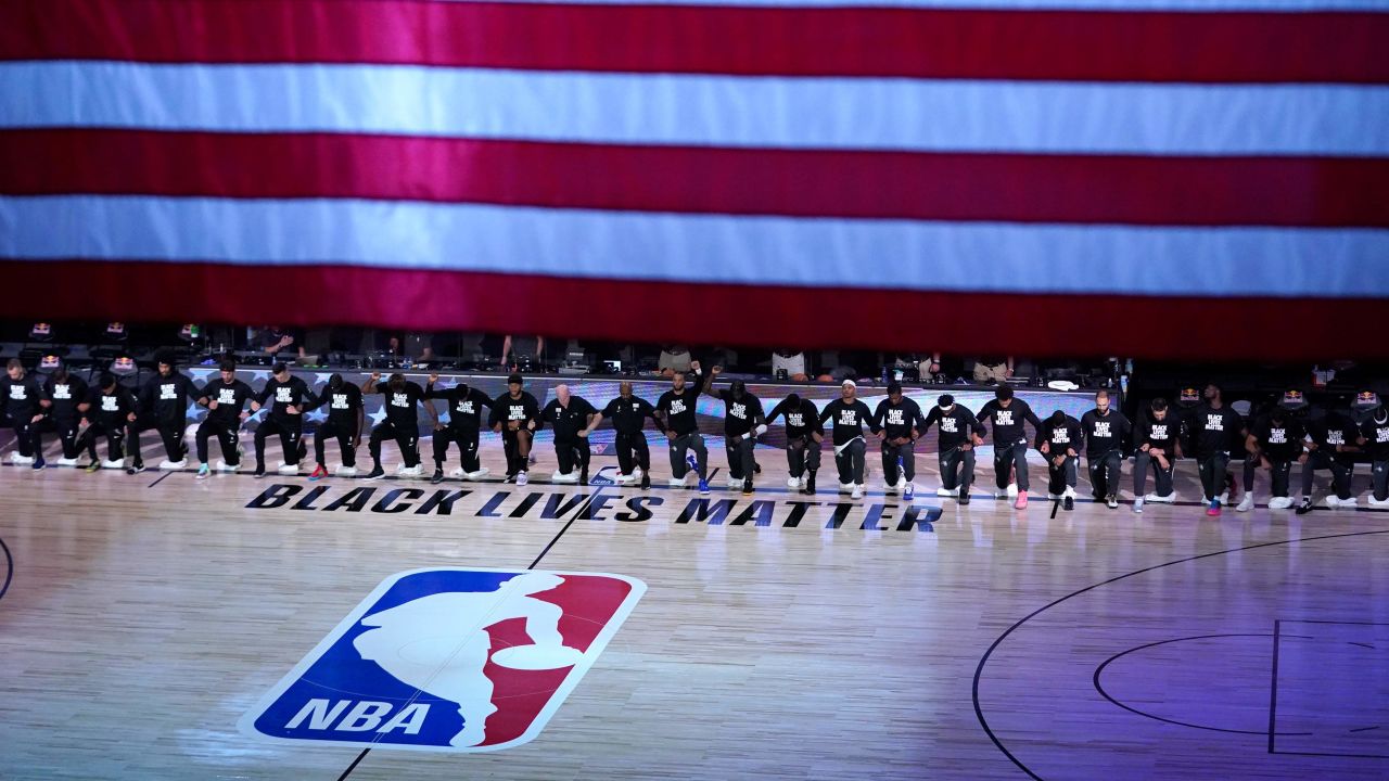 FILE - Members of the Orlando Magic and Brooklyn Nets kneel around a Black Lives Matter logo during the national anthem before the start of an NBA basketball game in Lake Buena Vista, Fla., in this Friday, July 31, 2020, file photo. As the NBA neared its restart in late July, its players vowed to keep the calls for social justice reform at the forefront in the wake of the deaths of George Floyd and Breonna Taylor.(AP Photo/Ashley Landis, Pool, File)