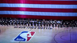FILE - Members of the Orlando Magic and Brooklyn Nets kneel around a Black Lives Matter logo during the national anthem before the start of an NBA basketball game in Lake Buena Vista, Fla., in this Friday, July 31, 2020, file photo. As the NBA neared its restart in late July, its players vowed to keep the calls for social justice reform at the forefront in the wake of the deaths of George Floyd and Breonna Taylor.(AP Photo/Ashley Landis, Pool, File)