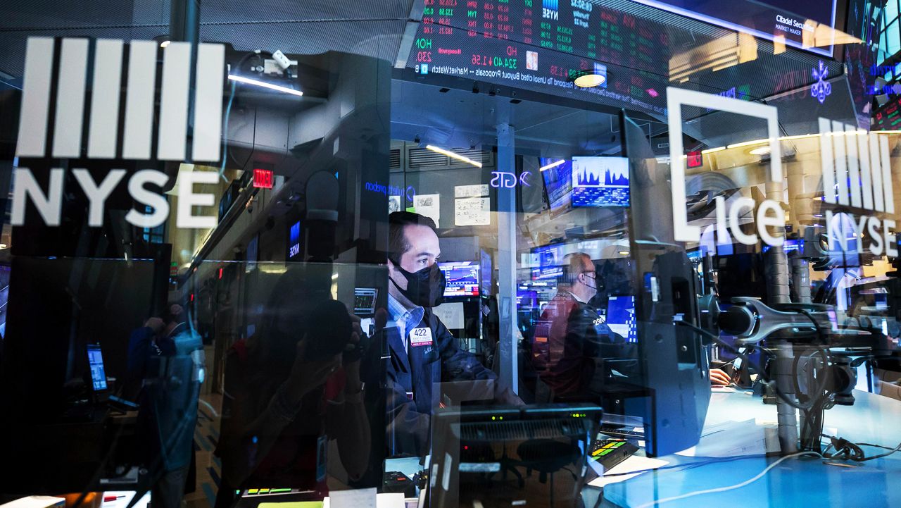 In this photo provided by the New York Stock Exchange, trader Robert Greason, left, right, works on the floor, Thursday April 22, 2021. Stocks wobbled between small gains and losses Thursday as investors continue to focus on company earnings reports and the economic recovery. (Courtney Crow/New York Stock Exchange via AP)