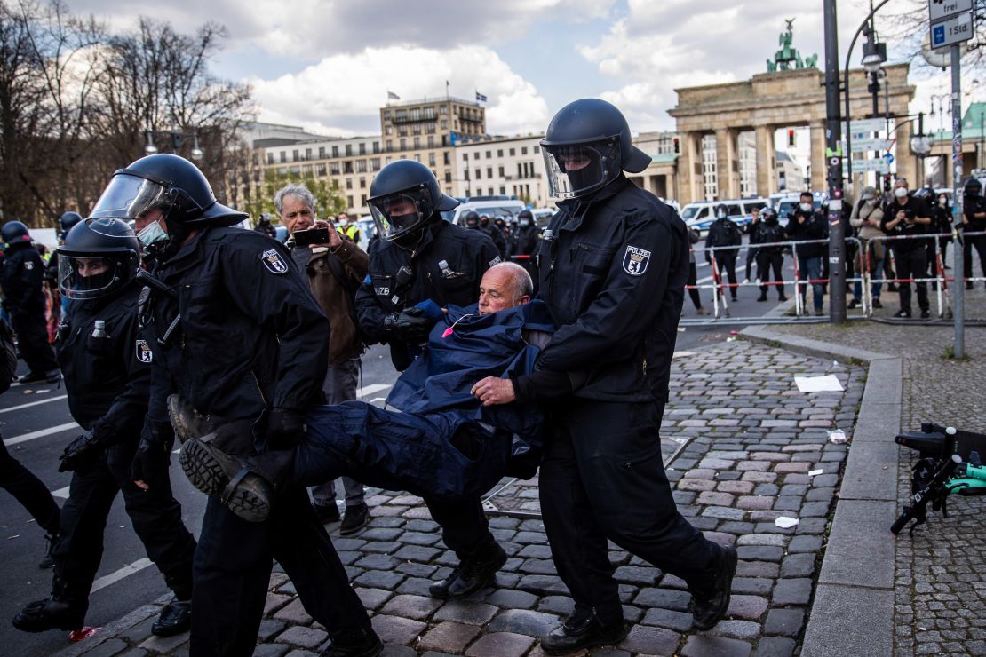 Police carry a demonstrator during protests against new legislative measures to rein in the coronavirus pandemic next to the Brandenburg Gate,  in Berlin, on April 21.
