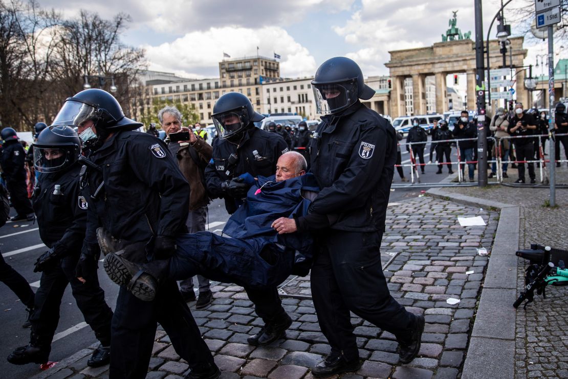 Police carry a demonstrator during protests against new legislative measures to rein in the coronavirus pandemic next to the Brandenburg Gate, in Berlin, on April 21.