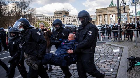 Police carry a demonstrator during protests against new legislative measures to rein in the coronavirus pandemic next to the Brandenburg Gate,  in Berlin, on April 21.