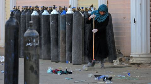 An Iraqi woman sweeps up debris Sunday next to oxygen bottles brought outside the Ibn Al-Khatib Hospital in Baghdad following Saturday night's fire.