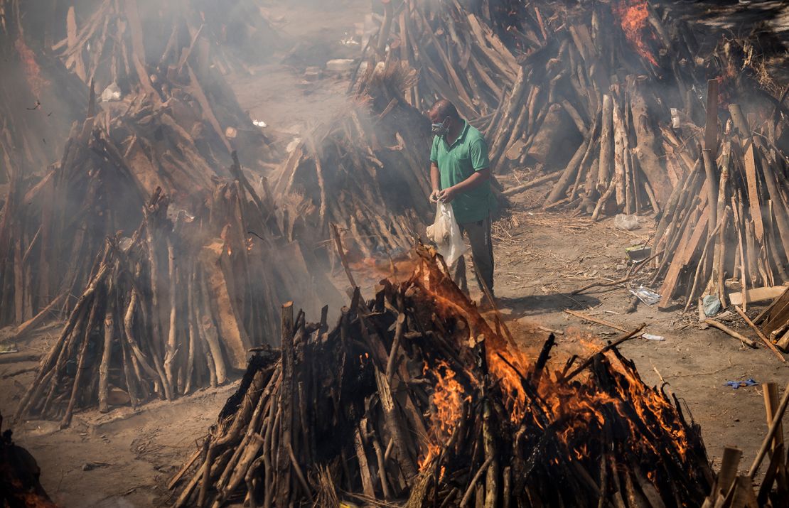 A man performs the last rites of a relative who died of Covid-19, as other funeral pyres are seen burning during a mass cremation in New Delhi, India, on April 24.