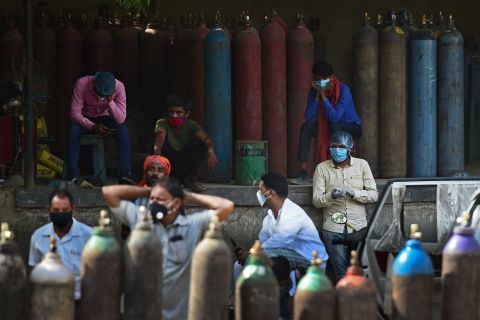 People wait to refill their oxygen cylinders at a refilling station in Allahabad on April 24.