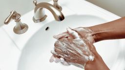 Woman lathers on the soap to wash hands in powder room sink