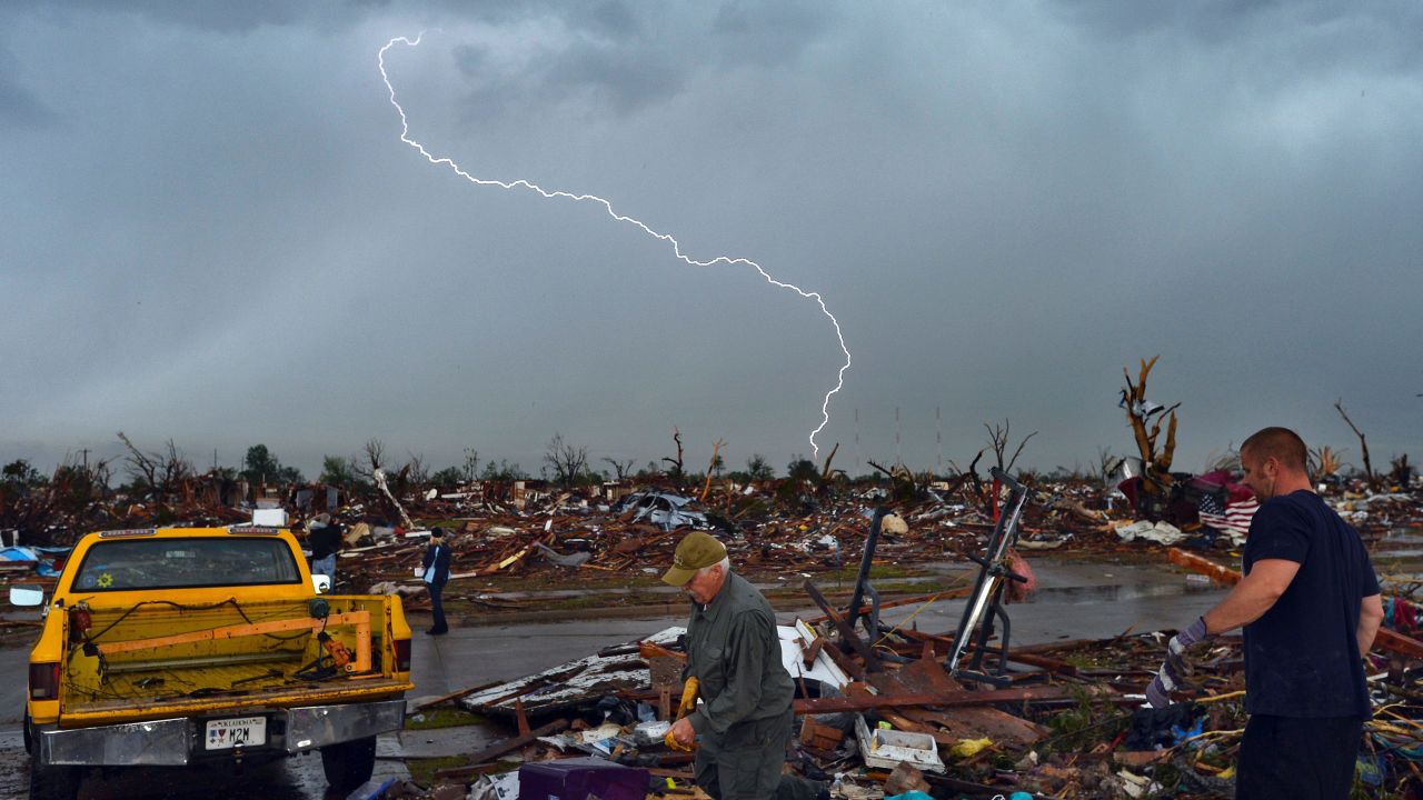Lightning strikes as tornado survivors search for salvagable items at their devastated home on May 23, 2013, in Moore, Oklahoma. Two dozen people died in a tornado there.