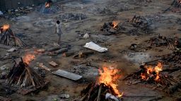 TOPSHOT - A man stands amid burning pyres of victims who lost their lives due to the Covid-19 coronavirus at a cremation ground in New Delhi on April 26, 2021. (Photo by Money SHARMA / AFP) (Photo by MONEY SHARMA/AFP via Getty Images)