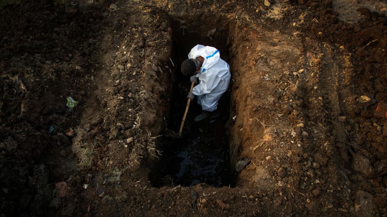 A man in protective suit digs earth to bury the body of a Covid-19 victim in Gauhati, India, on April 25.