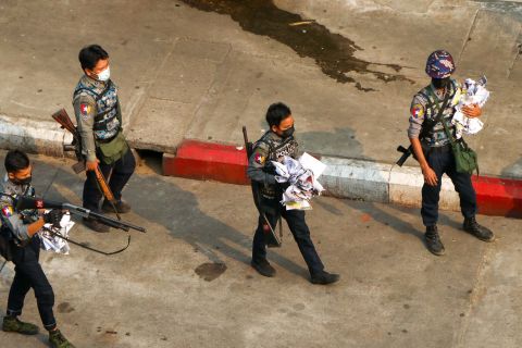 Police officers clear a road after demonstrators spread placards in Yangon on Saturday, April 24.
