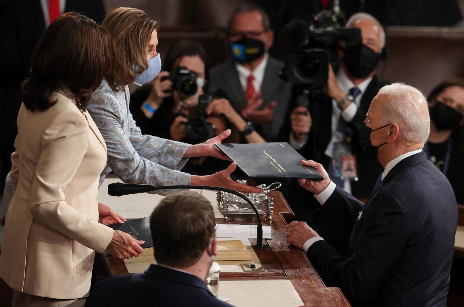 Biden hands a copy of his speech to Pelosi before he started it.