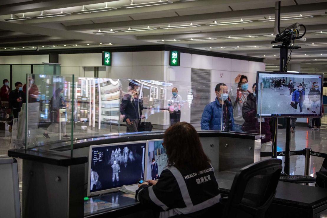 Airport health staff monitor the body temperatures of arriving passengers with thermal scanners in an arrival hall inside Hong Kong International Airport on February 21, 2020.