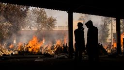 People are silhouetted against multiple burning funeral pyres of patients who died of the Covid-19 on April 24, 2021 in New Delhi, India. 