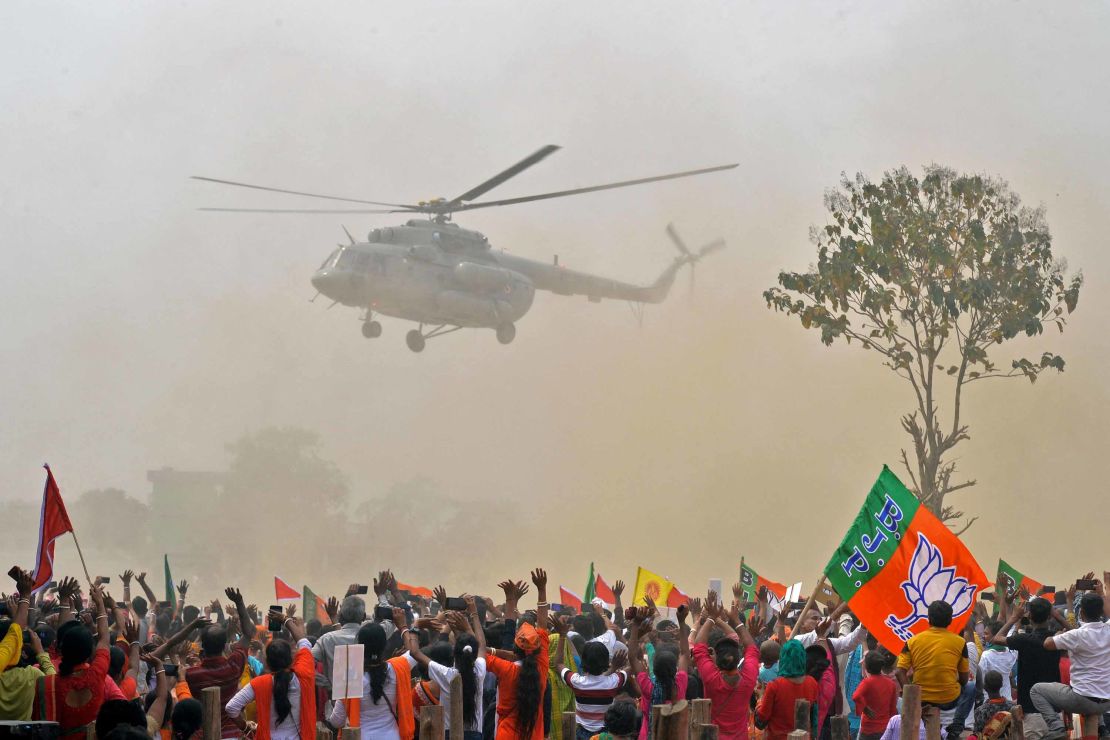 Supporters of Bharatiya Janata Party (BJP) wave towards a helicopter carrying Indian Prime Minister Narendra Modi upon his arrival at a public rally at Kawakhali on the outskirts of Siliguri on April 10, 2021. 