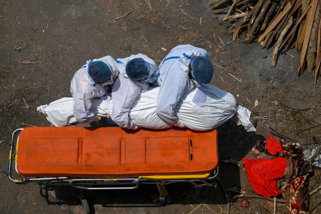 Family members and ambulance workers in protective equipment carry the body of a victim who died of the Covid-19 coronavirus at a cremation ground in New Delhi on April 27, 2021.