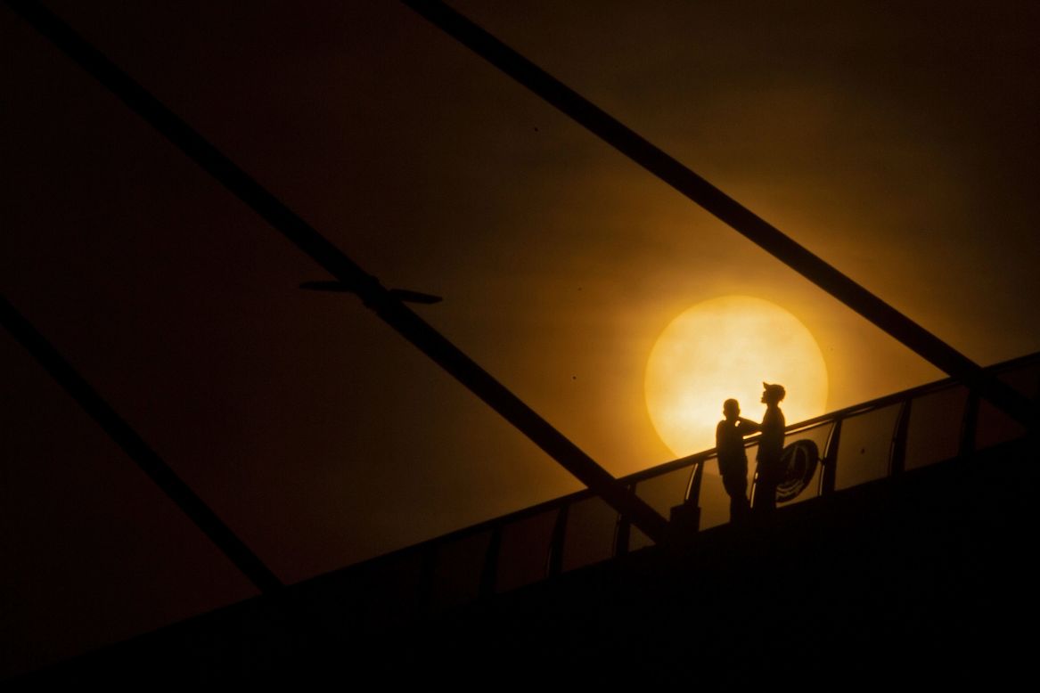 Men stand along the Mohammed Baqir al-Sadr bridge as the sun rises in Basra, Iraq, on Friday, April 23.