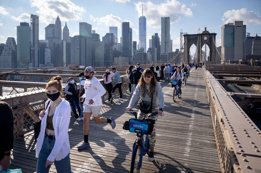 People walk and ride bicycles over the Brooklyn Bridge earlier this year. Vaccine mandates are going to be set up for indoor venues in New York City.
