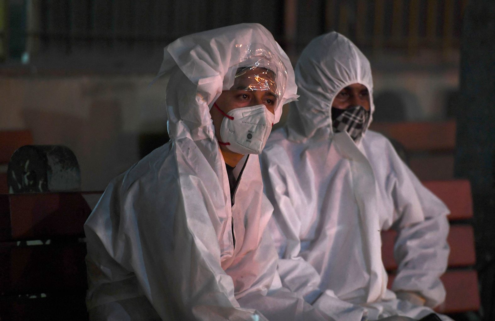 People wear protective suits while watching a relative's cremation in New Delhi on April 28. Their loved one died from Covid-19.