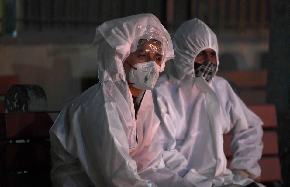 People wear protective suits while watching a relative's cremation in New Delhi on April 28. Their loved one died from Covid-19.