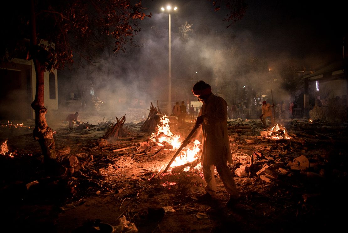 Workers can be seen at a crematorium where multiple funeral pyres are burning for people who lost their lives to Covid-19 on Thursday in New Delhi, India.