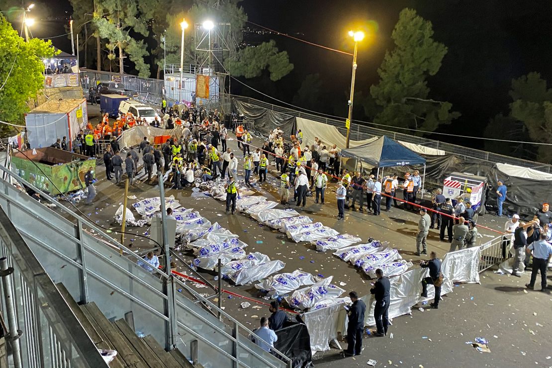 Israeli security officials and rescuers stand around the bodies of victims who died overnight on Mount Meron.