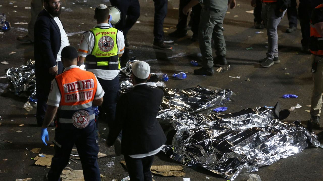 TOPSHOT - Paramedics and ultra-Orthodox Jewish men stand next to covered bodies after dozens of people were killed and others injured after a grandstand collapsed in Meron, Israel, where tens of thousands of people were gathered to celebrate the festival of Lag Ba'omer at the site in northern Israel early on April 30, 2021. - Dozens of people were killed in a stampede at a Jewish pilgrimage site in the north of Israel on early on April 30, rescue services said.  Tens of thousands of Jews were participating in the annual pilgrimage on Thursday, for the feast of Lag BaOmer. But after midnight, a grandstand collapsed, triggering scenes of panic. - Israel OUT (Photo by David COHEN / JINI PIX / AFP) / Israel OUT (Photo by DAVID COHEN/JINI PIX/AFP via Getty Images)