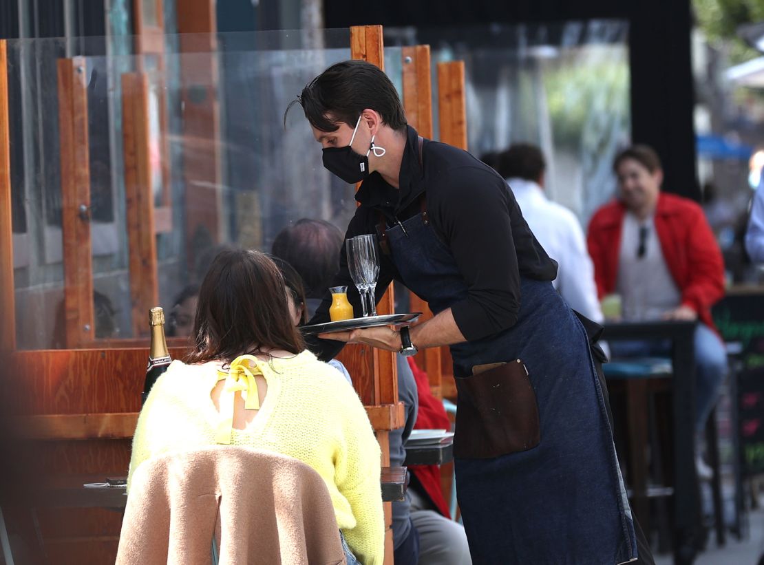 A waiter at serves guests dining outside in San Francisco.