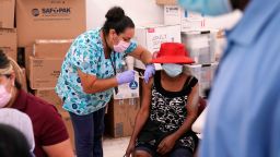 FILE - In this April 10, 2021, file photo, registered nurse Ashleigh Velasco, left, administers the Johnson & Johnson COVID-19 vaccine to Rosemene Lordeus, right, at a clinic held by Healthcare Network in Immokalee, Fla. With coronavirus shots now in the arms of nearly half of American adults, the parts of the U.S. that are excelling and those that are struggling with vaccinations are starting to look like the nation's political map: deeply divided between red and blue states. (AP Photo/Lynne Sladky, File)