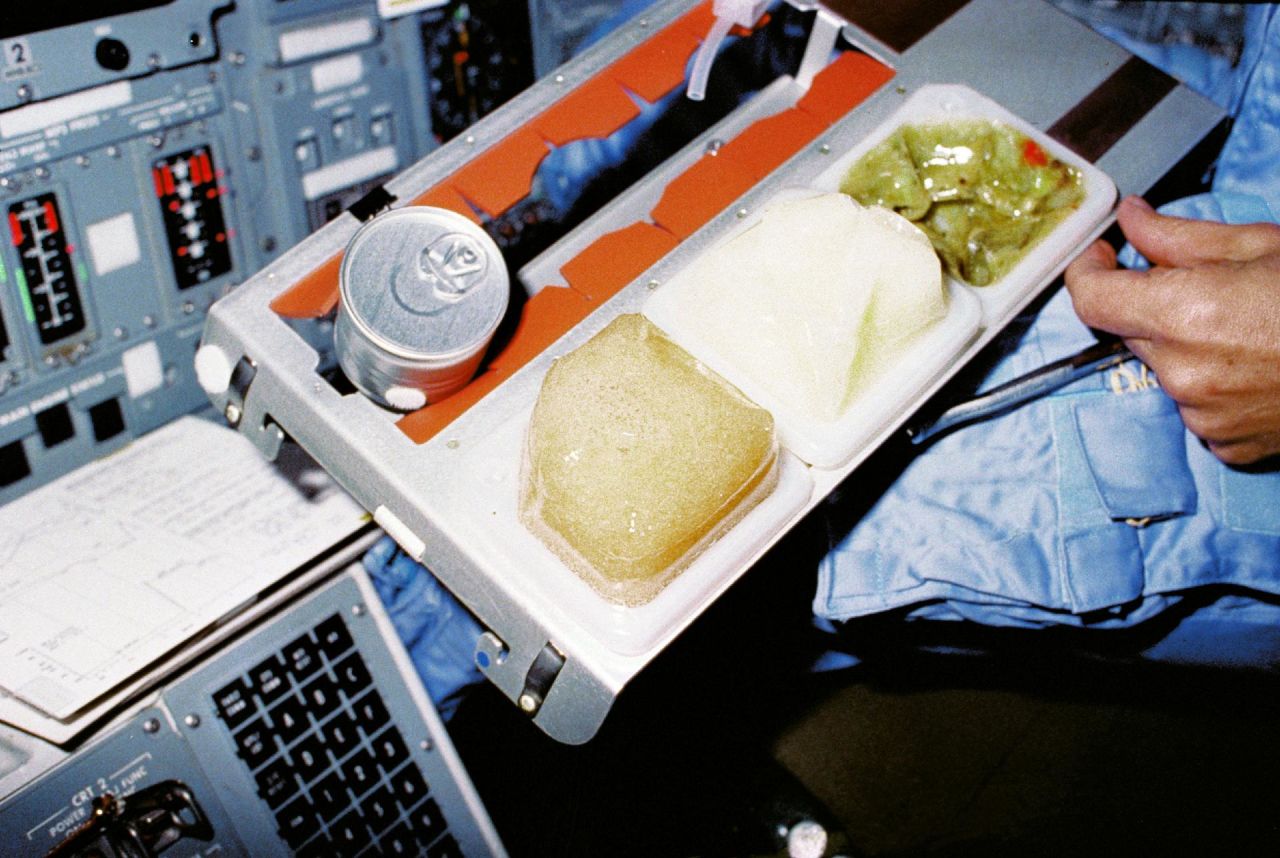 STS-9 was the space shuttle Columbia's sixth spaceflight, but it was the first opportunity for an onboard galley, located in the middeck. The metal tray made for easy prep and serving of in-space meals. This crew member is seated at the pilot's station on the flight deck in late 1983.