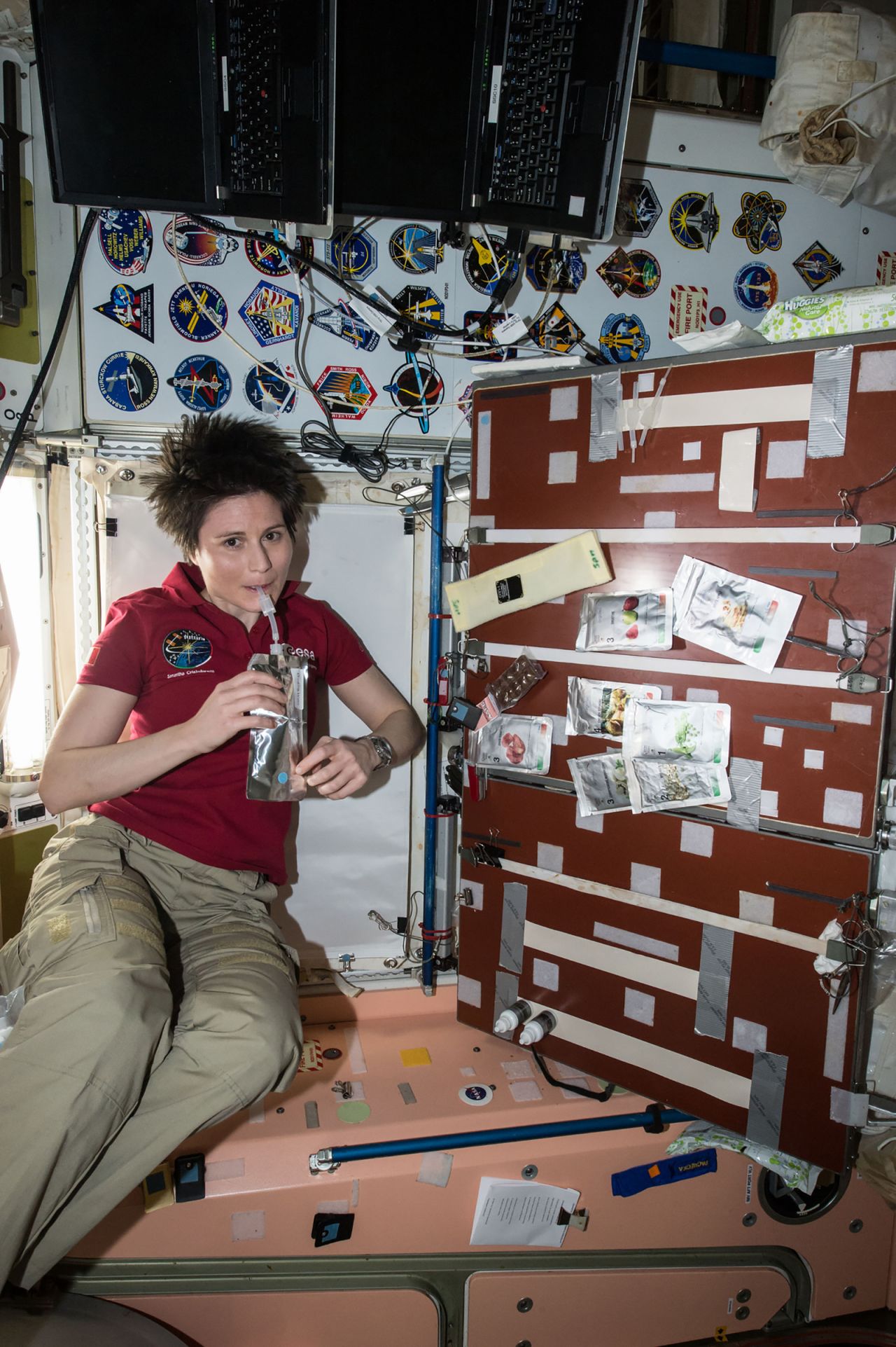 European Space Agency astronaut Samantha Cristoforetti is seen taking a drink in the Unity module aboard the International Space Station, April 27, 2015. The crew's food galley is located in Unity; several food packets are visible to the right.