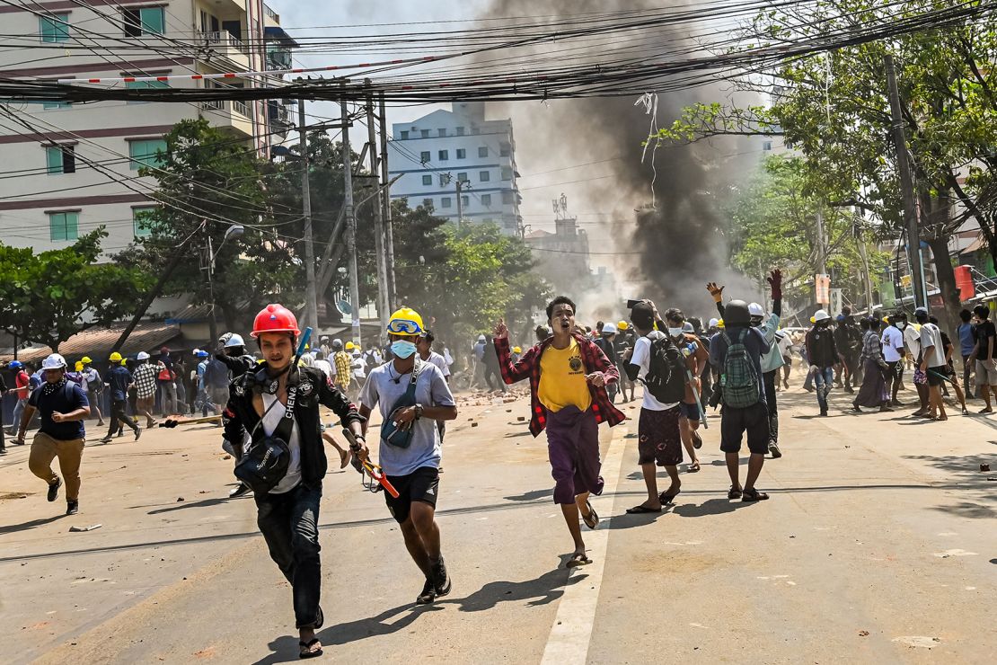 Protesters run as tear gas is fired during a crackdown by security forces on a demonstration against the military coup in Yangon's Thaketa township on March 19.