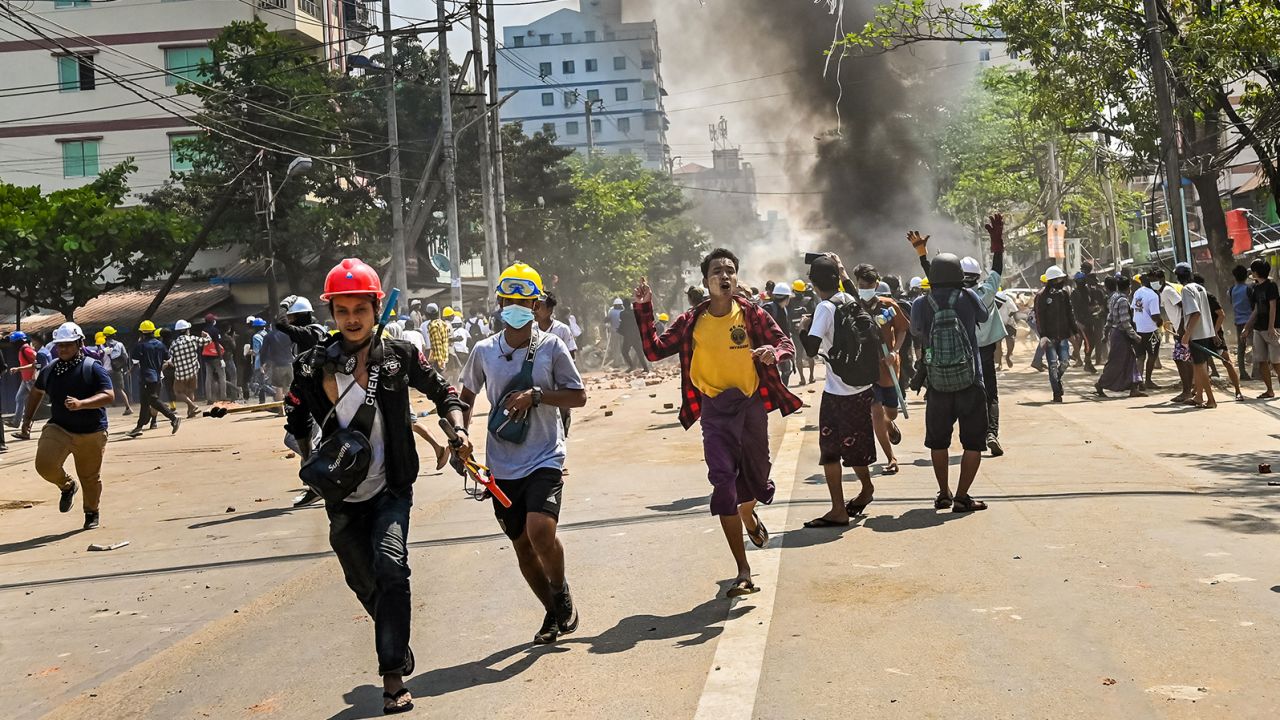 Protesters run as tear gas is fired during a crackdown by security forces on a demonstration against the military coup in Yangon's Thaketa township on March 19.