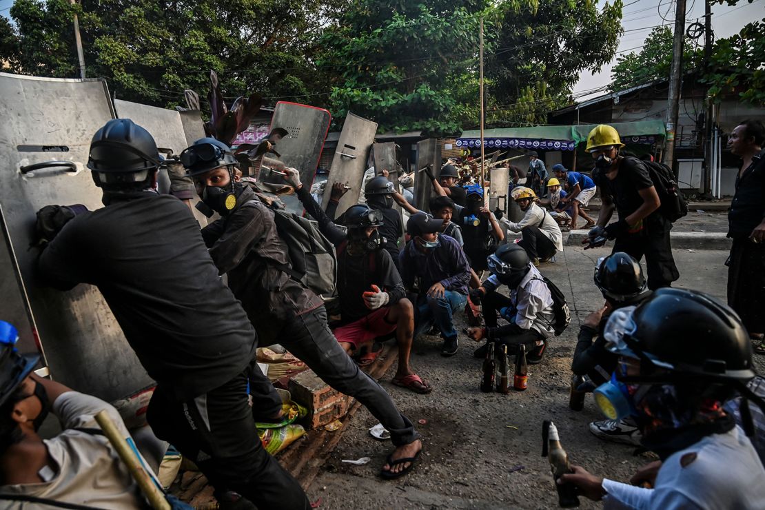  Protesters take cover behind homemade shields as they confront the police during a crackdown on demonstrations against the military coup in Yangon on March 16.