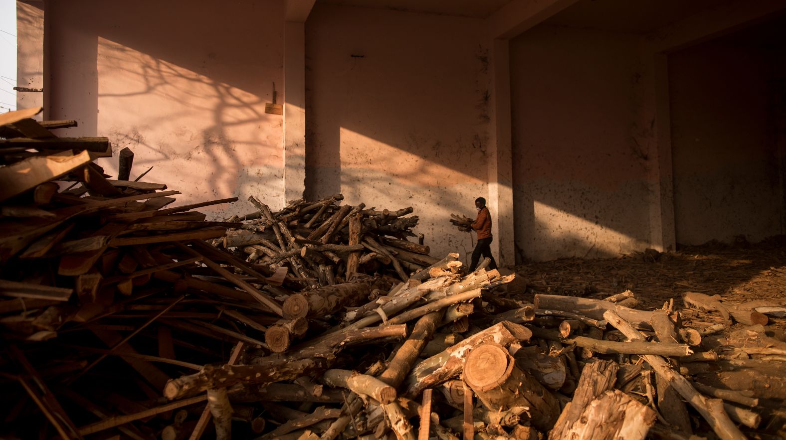 A worker at a mass crematorium carries logs of wood for funeral pyres as people perform the last rites for some Covid-19 victims in New Delhi on May 1.