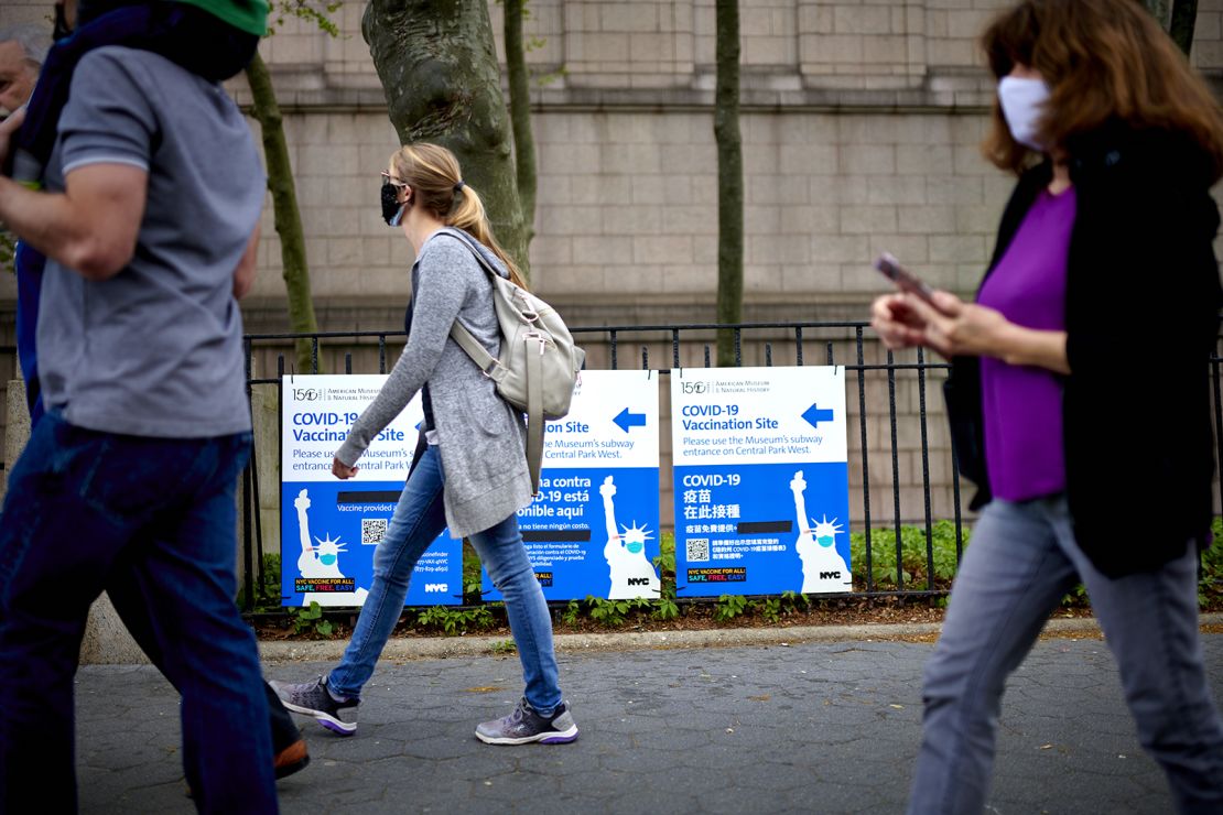 Pedestrians pass in front of Covid-19 vaccination site signs outside the American Museum of Natural History in New York on Friday.
