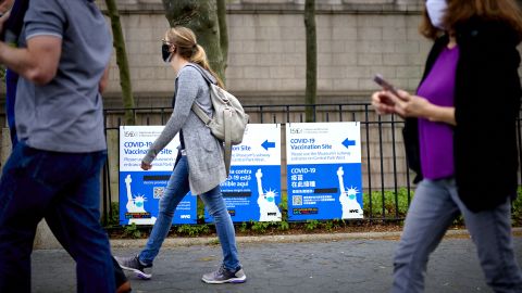 Pedestrians pass in front of Covid-19 vaccination site signs outside the American Museum of Natural History in New York on Friday.