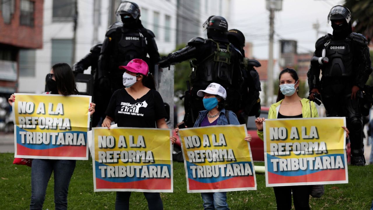 Women hold banners reading "No to tax reform" as police stand guard.