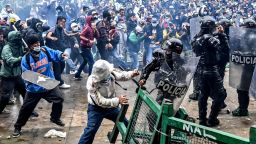 TOPSHOT - Demonstrators clash with riot police during a protest against a tax reform bill launched by Colombian President Ivan Duque, in Bogota, on April 28, 2021. - Workers' unions, teachers, civil organizations, indigenous people and other sectors reject the project that is underway in the Congress, considering that it punishes the middle class and is inappropriate in the midst of the crisis unleashed by the COVID-19 pandemic. (Photo by Juan BARRETO / AFP) (Photo by JUAN BARRETO/AFP via Getty Images)