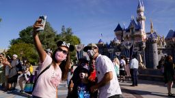 A family takes a photo in front of Sleeping Beauty's Castle at Disneyland in Anaheim, Calif., Friday, April 30, 2021.  The iconic theme park in Southern California that was closed under the state's strict virus rules swung open its gates Friday and some visitors came in cheering and screaming with happiness. (AP Photo/Jae Hong)
