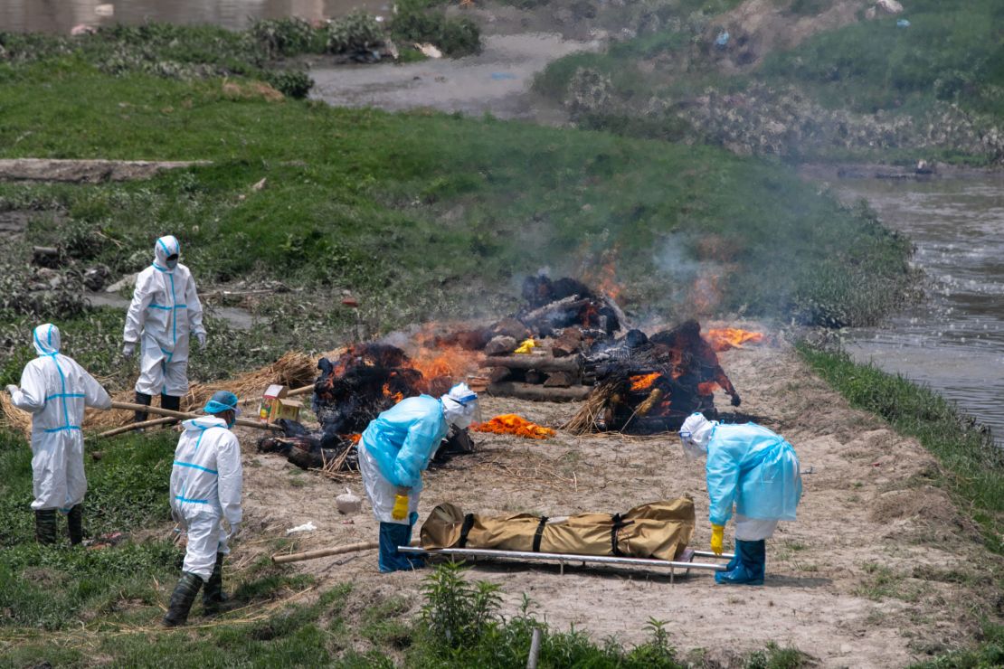 Nepali men in personal protective suits cremate the bodies of Covid-19 victims near Pashupatinath temple in Kathmandu, Nepal, on May 3, 2021. 