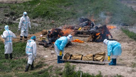 Nepali men in personal protective suits cremate the bodies of Covid-19 victims near Pashupatinath temple in Kathmandu, Nepal, on May 3, 2021. 