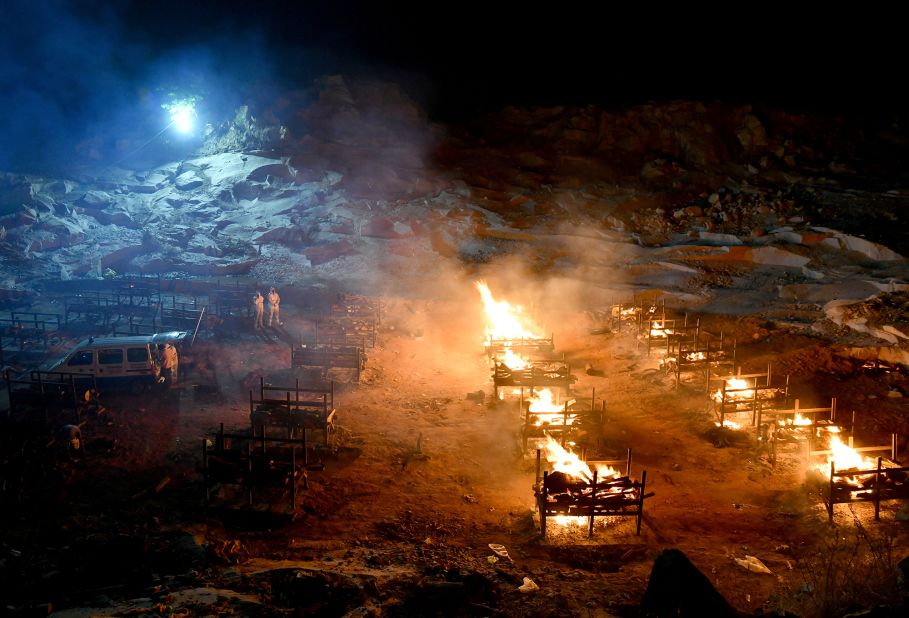 Volunteers stand next to burning pyres at a crematorium on the outskirts of Bengaluru on May 2.