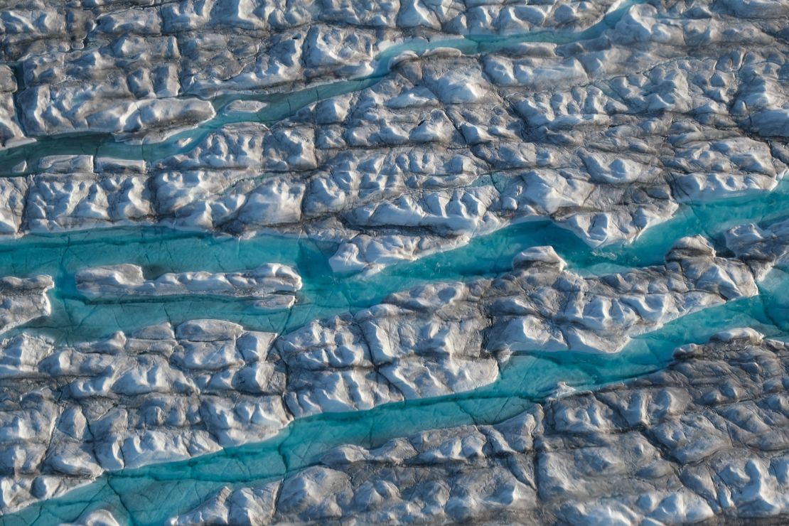 Rivers of meltwater carve into the Greenland ice sheet. A new study finds that limiting warming to below 1.5 degrees Celsius could cut sea level rise caused by melting land ice this century in half.